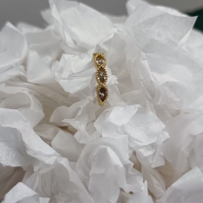 Anel dourado com pedras castanhas em papel branco