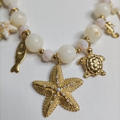 Colar com contas creme e rosa e pendentes dourados de temas marinhos