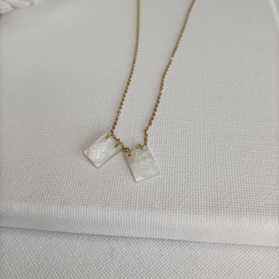 Colar com dois pendentes retangulares em madrepérola e corrente dourada sobre tecido branco