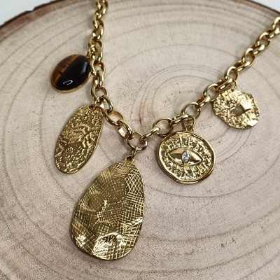 Colar dourado com correntes e pendentes variados sobre base de madeira clara