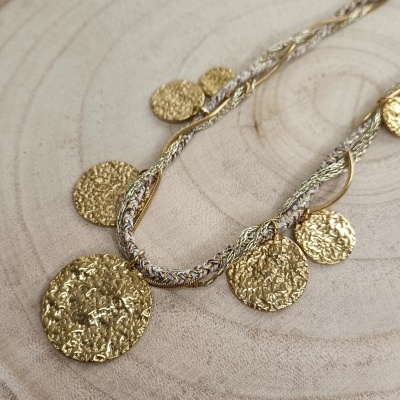 Colar com pendentes redondos dourados texturizados sobre madeira clara