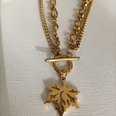 Colar dourado com pendente de folha e fecho de barra