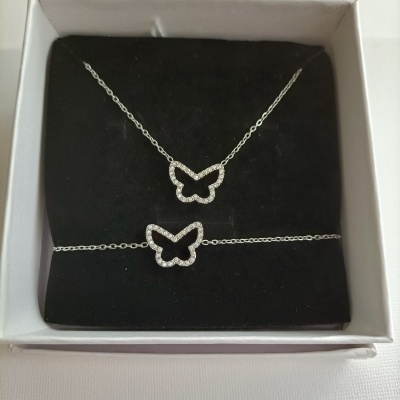 Conjunto de colar e pulseira com pendentes de borboleta em cristais numa caixa.