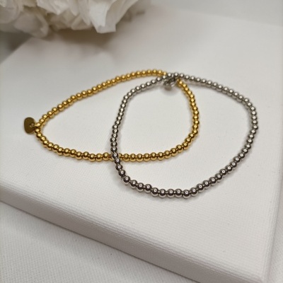 Dois colares de contas dourado e prateado sobre superfície branca texturada