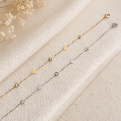 Duas pulseiras delicadas, dourada e prateada, com detalhes de círculos e pedras brilhantes