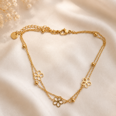 Colar dourado com flores e contas sobre tecido creme