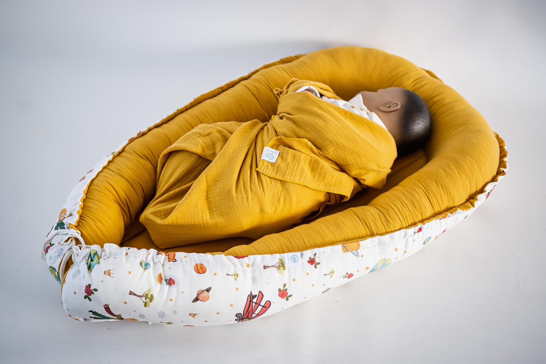 Ninho Principezinho Bebé em ninho almofadado com padrão colorido e tecido amarelo