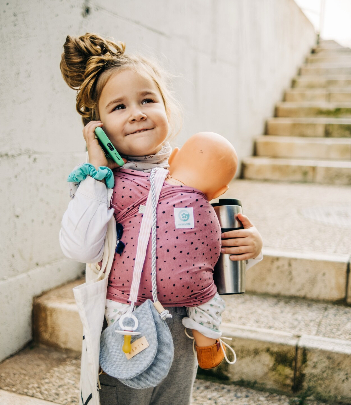 ISling4kid - Porta-bonecas Criança com porta-bebés rosa carregando boneca em escadas de pedra