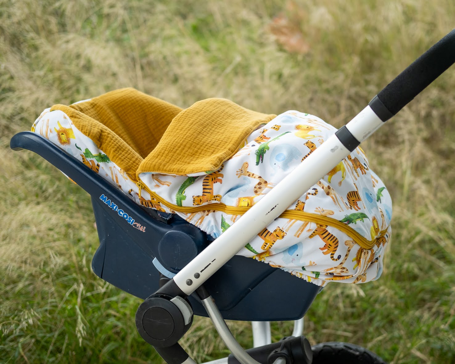 Forra OVO Jungle Assento de criança com cobertor amarelo e capa estampada com girafas num carrinho ao ar livre
