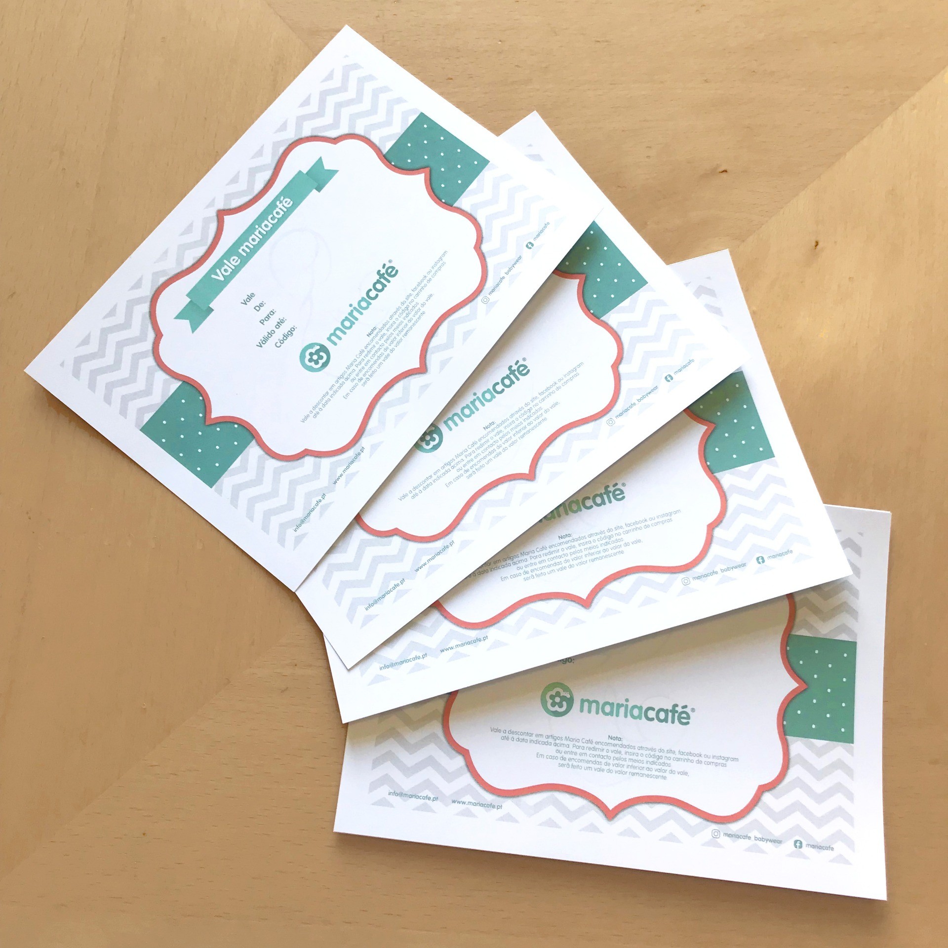 Cartão Presente Maria Café Cartões com design branco, verde e vermelho e texto em português sobre mesa de madeira clara