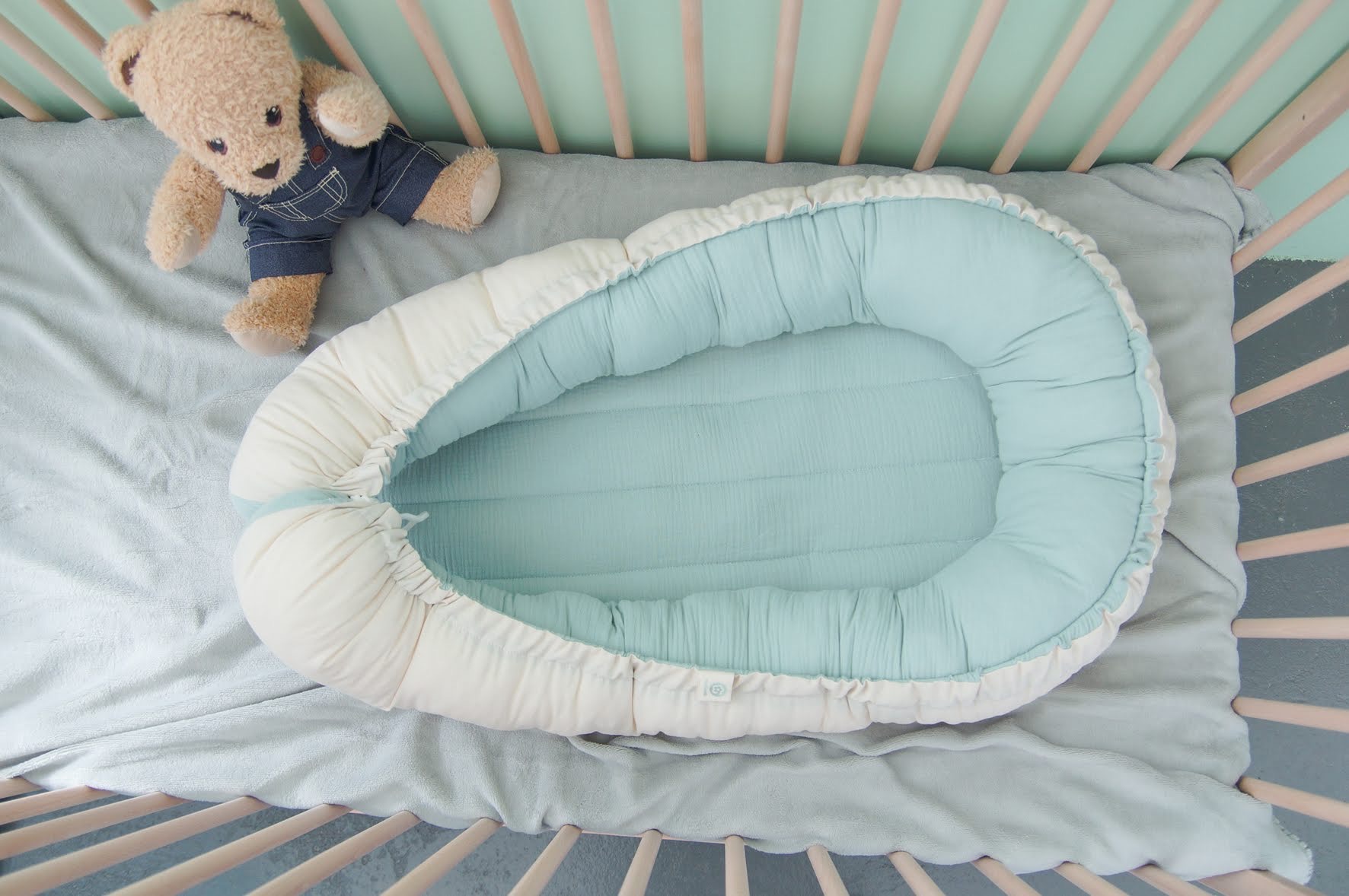 Ninho Cru Berço azul claro com ninho de bebê e urso de peluche