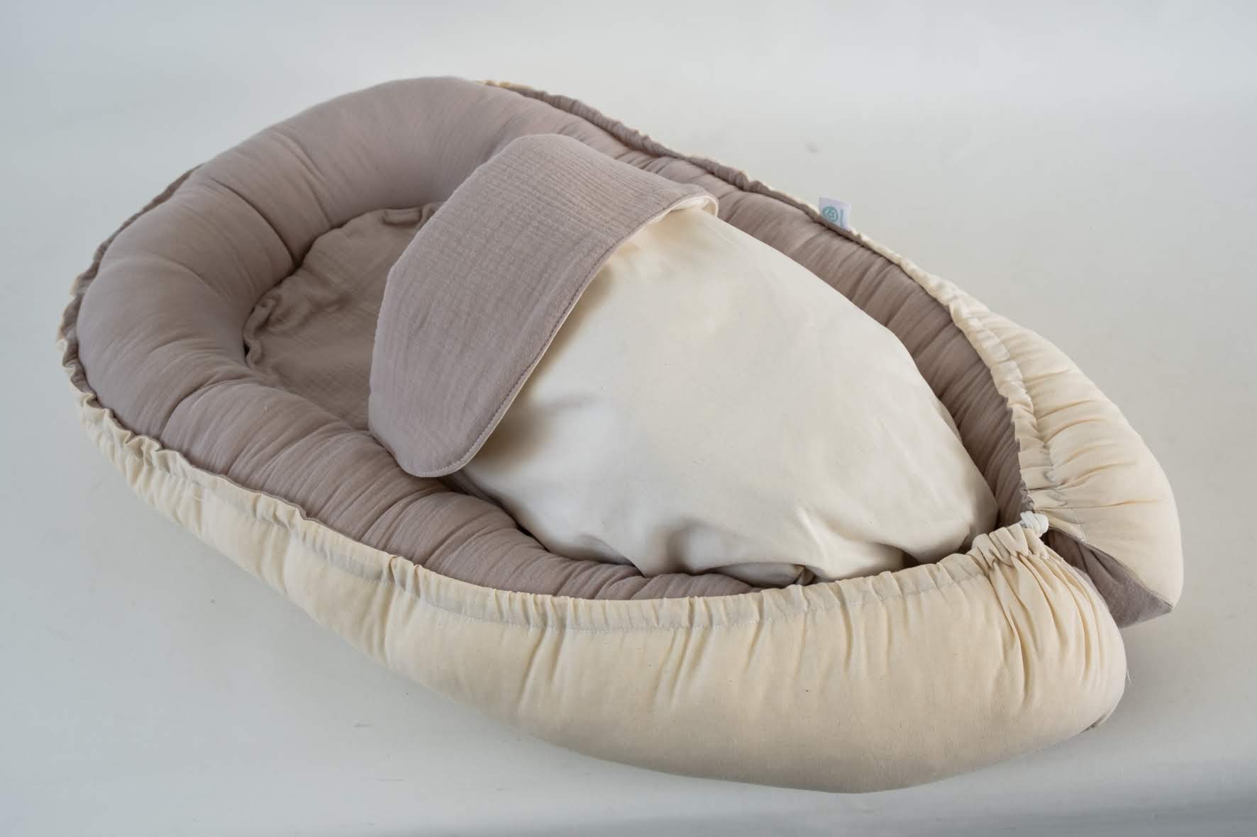 Ninho Cru Berço portátil almofadado em tons bege e castanho claro com almofada