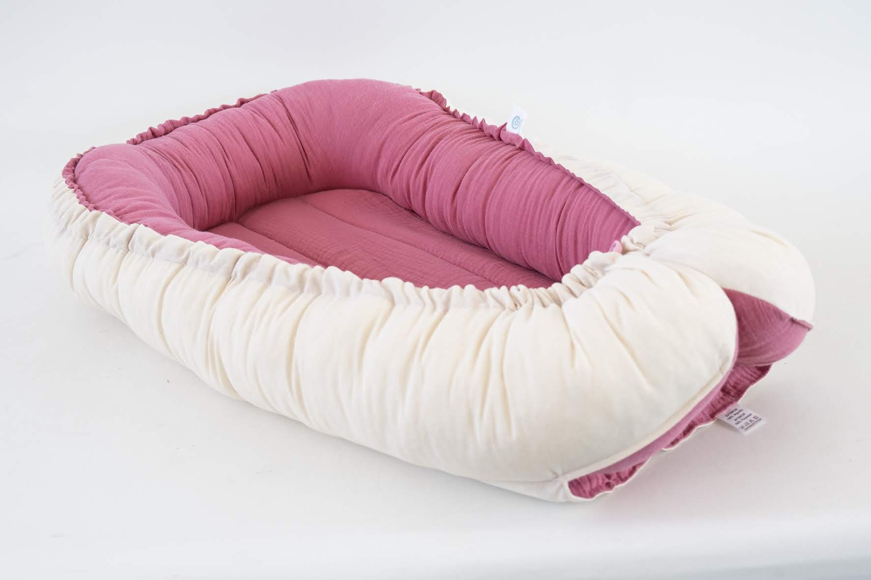 Ninho Cru Ninho para bebé rosa e bege sobre fundo branco