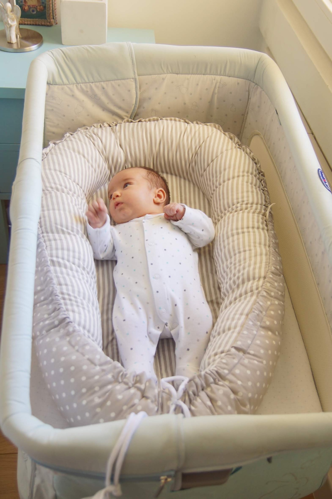 Ninho mix de padrões Berço portátil azul claro acolchoado com bebê em pijama branco dentro