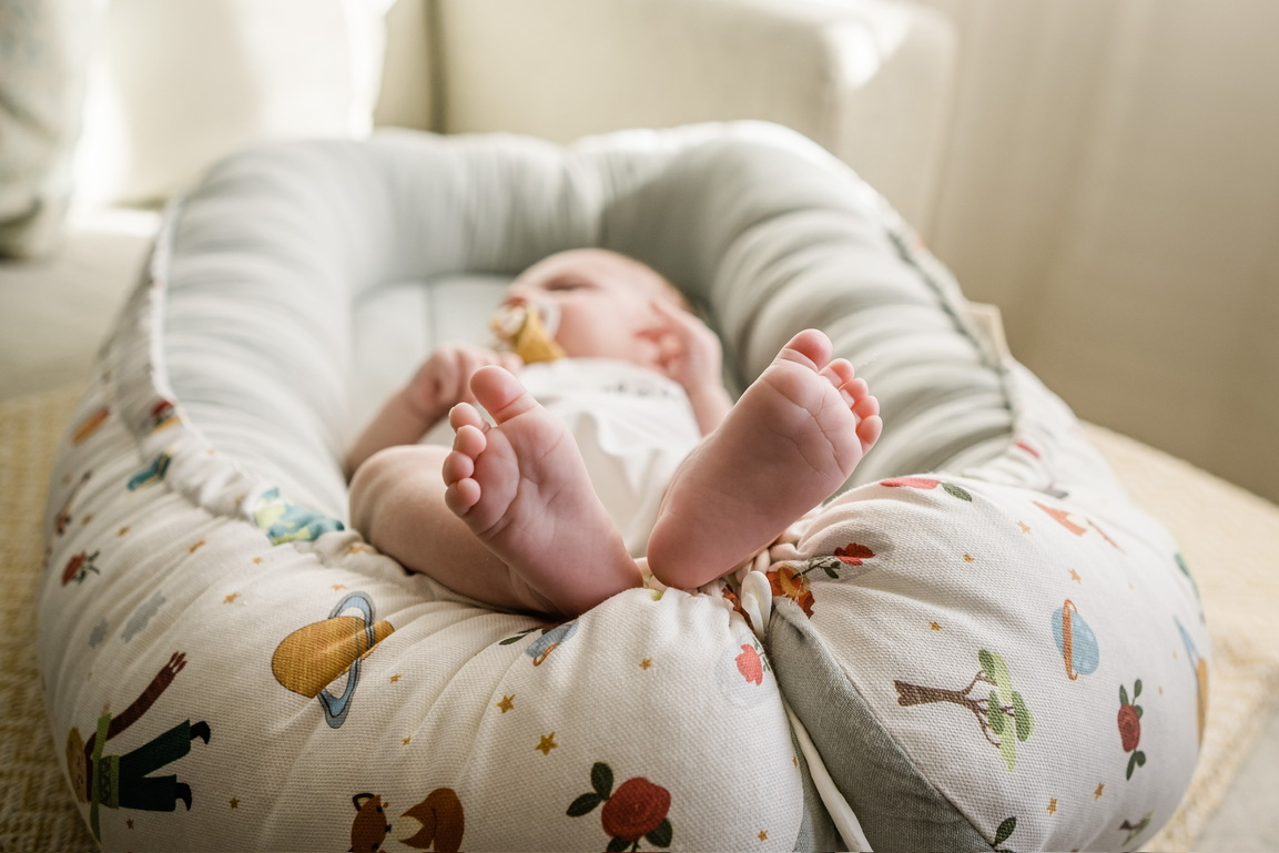 Ninho Principezinho Bebé deitado num ninho para bebés com padrão colorido