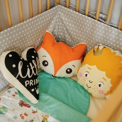 Almofadas infantis coloridas dentro de um berço de madeira com roupa de cama colorida