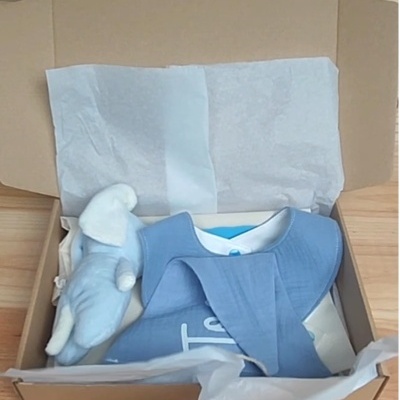 Caixa aberta com roupas e boneco de pelúcia para bebé