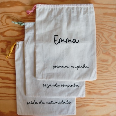 Três sacos de tecido com cordões coloridos e texto em português