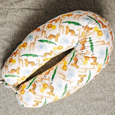 Almofada de amamentação com padrão de animais coloridos sobre fundo branco