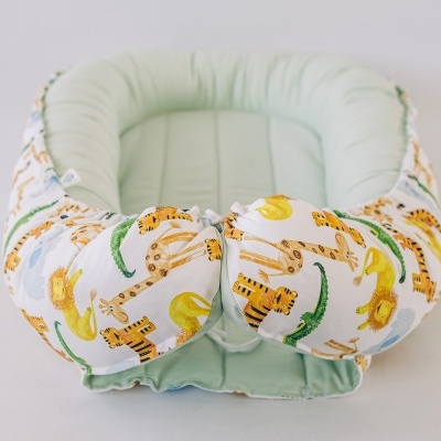 Ninho para bebé com estampado de animais em tecido, interior verde água.