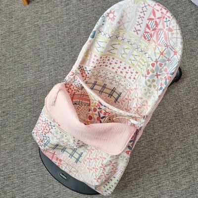 Cadeira de descanso para bebé estampada com almofada rosa em chão de carpete cinzenta