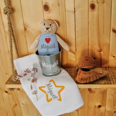 Ursinho de peluche e itens de bebé personalizados com o nome Miguel, sobre banco de madeira