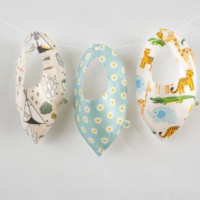 Três babetes de bebé com padrões diferentes pendurados numa corda