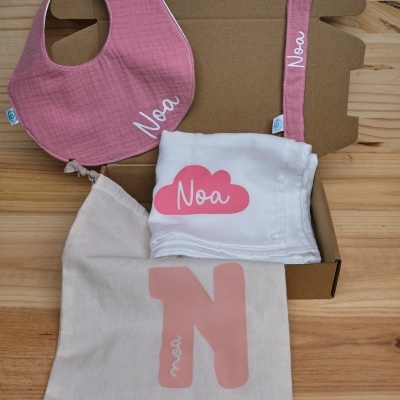 Conjunto para bebé com babete, faixa, fralda e saco personalizados com o nome Noa, em tons de rosa e branco