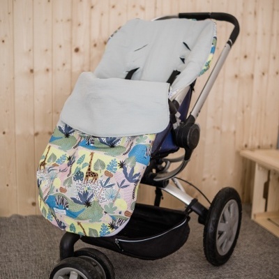 Carrinho de bebé colorido com padrão de animais e vegetação, almofada cinzenta, em ambiente com parede e chão de madeira