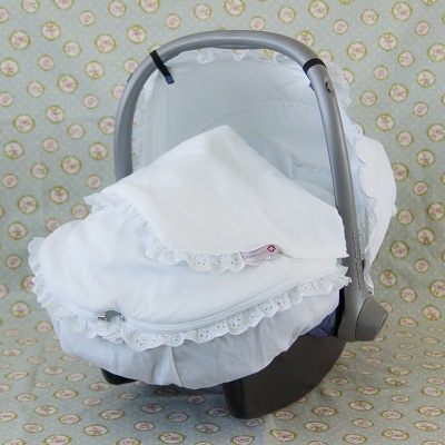 Alcofa cinzenta com cobertor e lenço branco com renda sobre fundo floral e texto mari