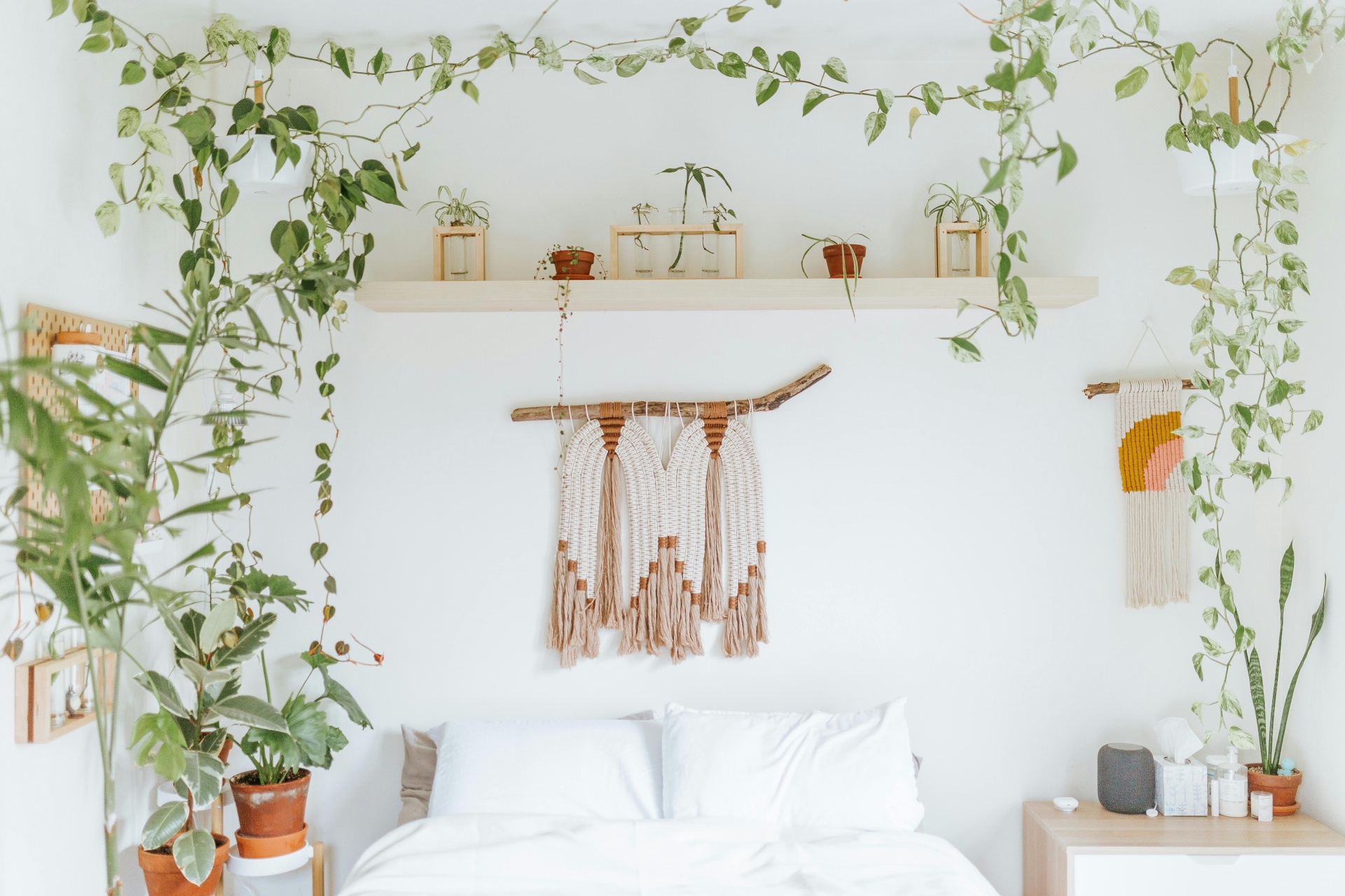 Quarto branco com cama e decorações naturais e tapeçaria na parede