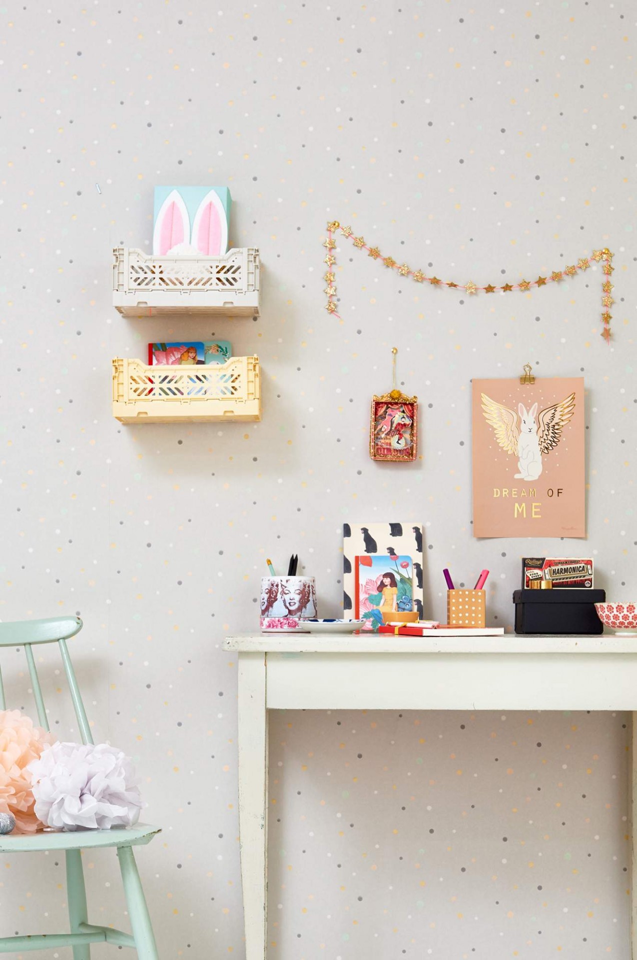 Espaço de trabalho com secretária branca, papel de parede claro com pontos coloridos, prateleiras de parede e cadeira verde claro com pompons