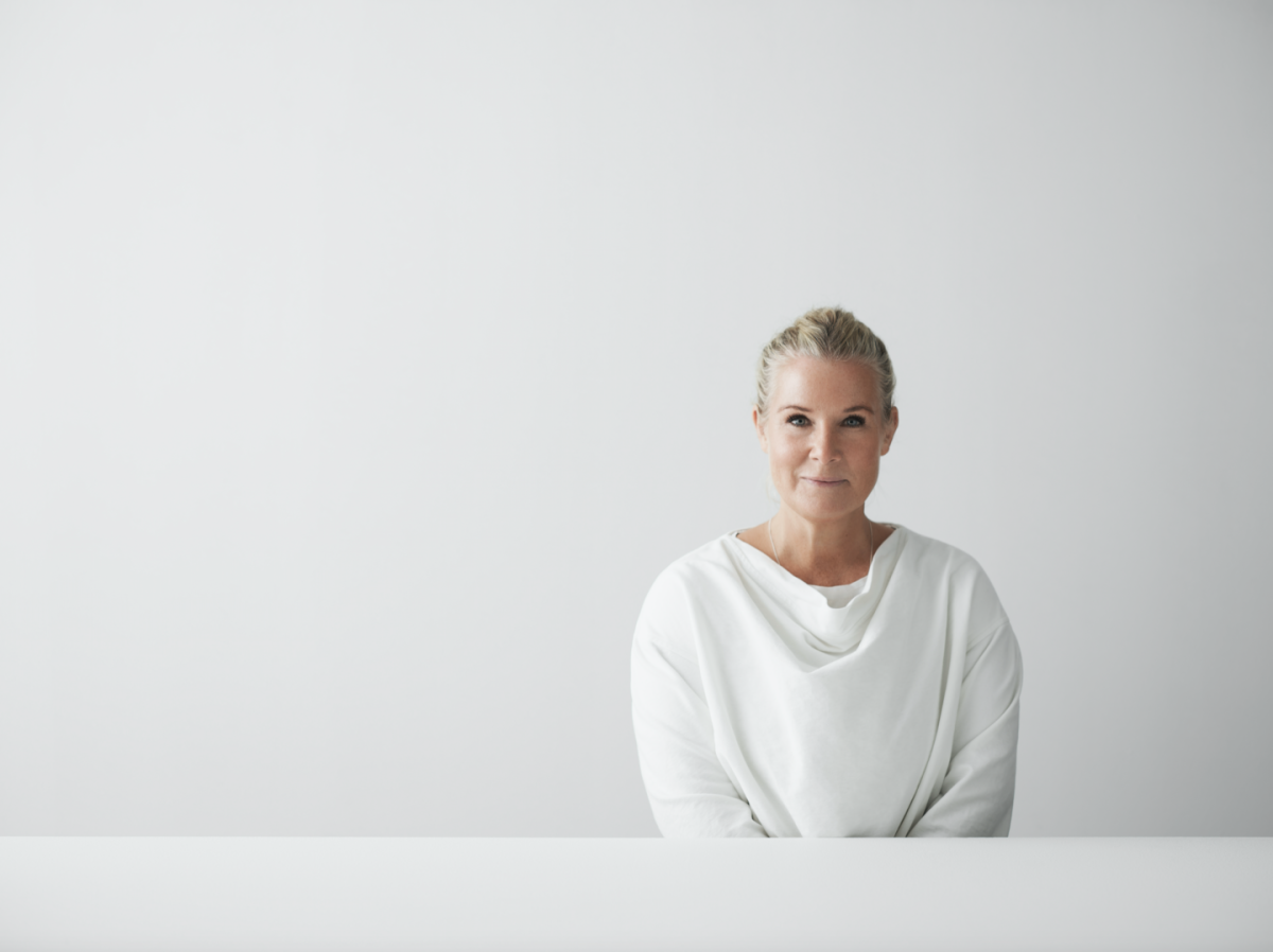 mulher de cabelo loiro com casaco branco em fundo branco minimalista