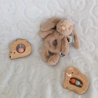 Brinquedos infantis de pelúcia e madeira sobre tecido branco texturizado
