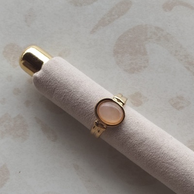 Anel dourado com pedra oval cor salmão em caixa de veludo cinzento claro