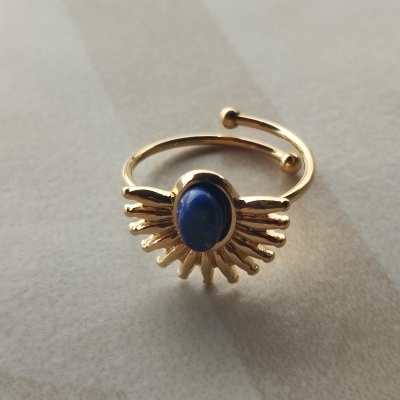 Anel dourado com pedra azul e design de raios solares