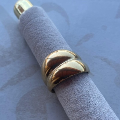 Anel dourado liso com design duplo curvado sobre suporte cinza claro