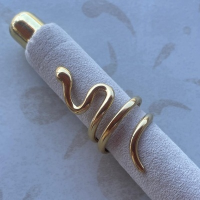 Anel dourado ondulado em suporte de veludo cinza