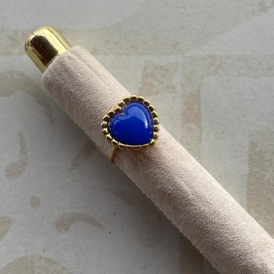 Anel com pedra azul coração e moldura dourada em suporte almofadado bege