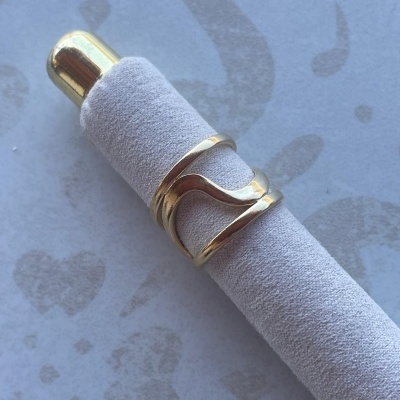 anel dourado em suporte cinza com fundo padrão musical