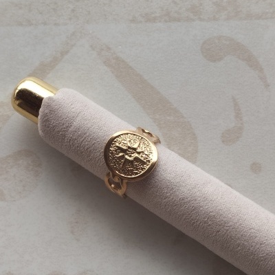 Anel dourado com disco gravado e almofada de veludo cinza
