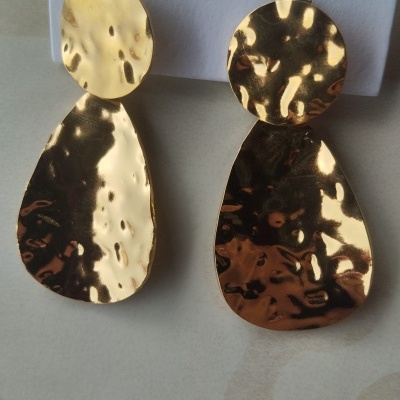 Par de brincos dourados martelados com formas redonda e oval.
