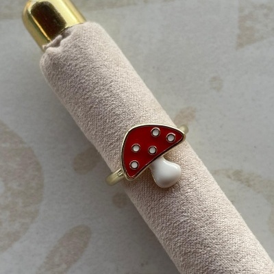 Anel dourado com símbolo de cogumelo vermelho com manchas brancas