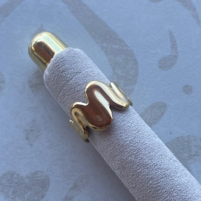 Anel dourado ondulado sobre haste de veludo cinzenta clara