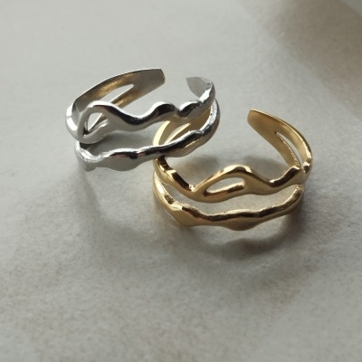 Dois anéis metálicos abertos, prateado e dourado, com design ondulado.