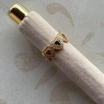 Anel dourado com pedras em forma de coração várias cores em suporte creme aveludado