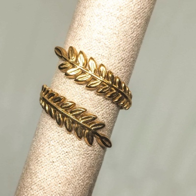 Anel dourado com design de folhas em suporte de tecido bege