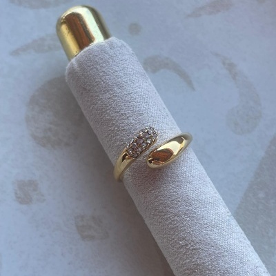 Anel dourado com pedras sobre base cilíndrica cinza claro