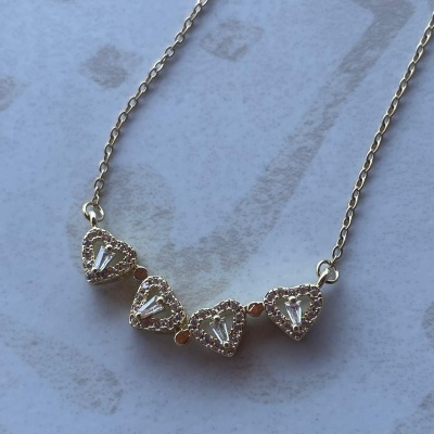 Colar dourado com quatro pendentes em forma de coração com pedras brancas
