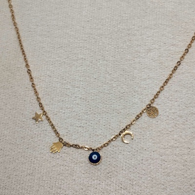 colar dourado com pendentes variados sobre tecido bege